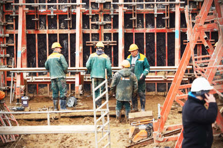 Workers in green uniform on construction site with scaffolding armature in Lithuania, Europe