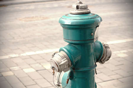 Green fire hydrant on paved street road sidewalkの写真素材