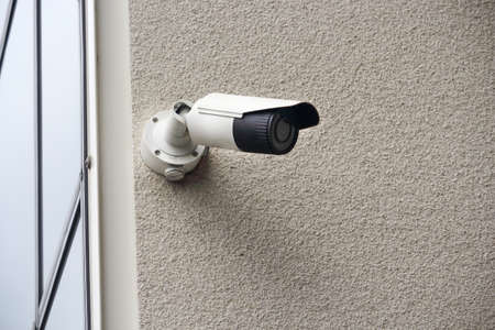 Outdoor video security camera on concrete wall of modern building corner