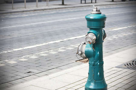 Green fire hydrant on paved street road sidewalkの写真素材
