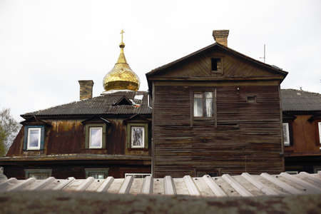Old aged wooden brown house roofs and golden church behindの写真素材