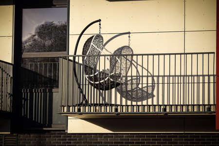 Woven hanging chair on residental building balcony with shadowの写真素材