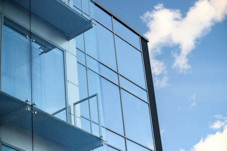Glass building with blue sky and clouds reflection in windows