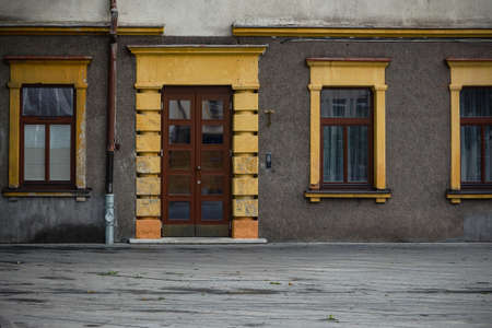 Gray building facade with yellow bricks and brown door