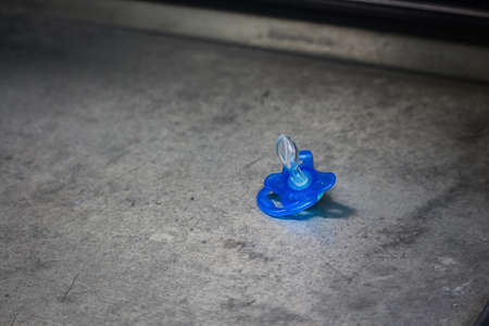 Blue kids pacifier dummy left on concrete surfaceの写真素材