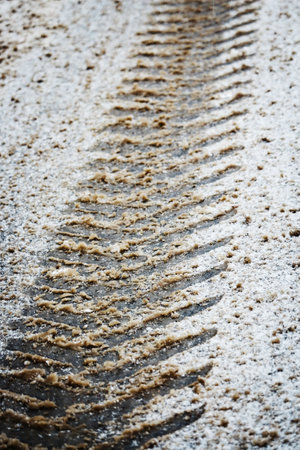 Wide wheel trace on frozen dirt road covered with snowの写真素材