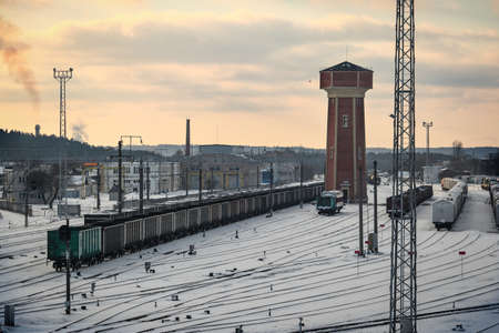 Railways with train in winter with big red brick tower in bright sunset