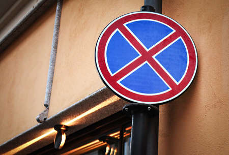 No stopping round road sign hanging on brown concrete wall building corner