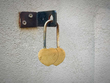 Two hearts padlock love symbol hanging on white textured wall