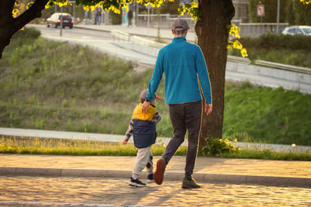 Father and son crossing an old rocky road in sunset lightの写真素材