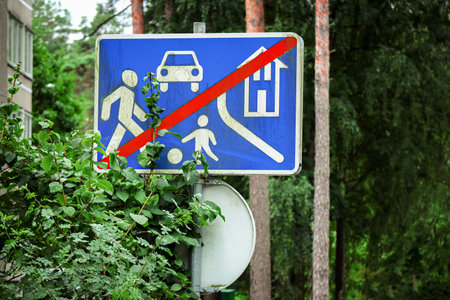 Sign of speed reduction near the local area crossed by red line standing near leafy hedge on park backgroundの写真素材