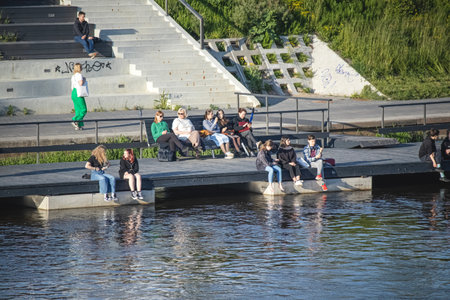 Vilnius, Lithuania 03 06 2022: Young people and seniors sitting near Neirs river chilling in sepia warm sunset lightのeditorial素材