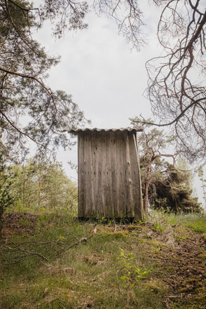 Little wooden wc house in a countryside, wc toilet old booth outside near forestの写真素材