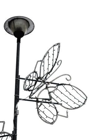Big wire butterfly light hanging on a street light pole on white winter sky backgroundの写真素材