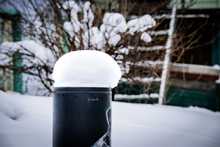 Big fluffy soft snowdrift on a black post with digits in a snowy winter near cottage building with stairsの写真素材