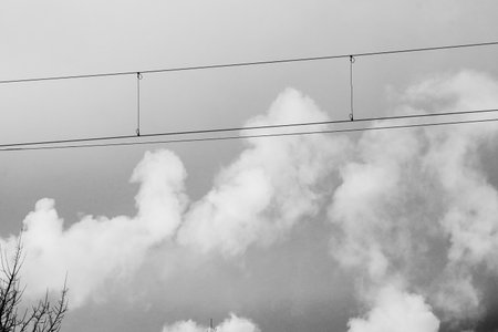 Double wires with fluffy smoke pieces on grey winter sky backgroundの写真素材