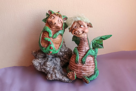 Two handmade dolls of green mama and baby dragons with wings on peach backgroundの写真素材