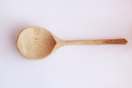 Wooden spoon in sunlight on white backgroundの写真素材