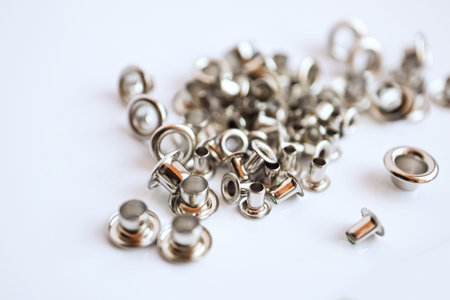 Metal silver eyelets on white table with bokeh blur in bright day lightの写真素材