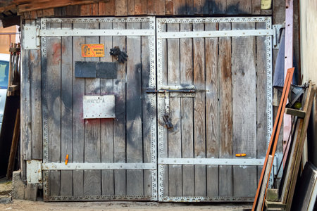 Old wooden gate door with a lock and metal plate saying Angry Dog in Lithuanian and a post box with a handwritten Post writing in Russianの写真素材