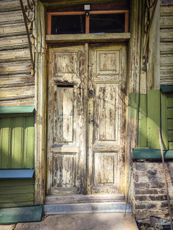 Old building wooden door with textured surface, a horizontal hole for mail and a round handleの写真素材