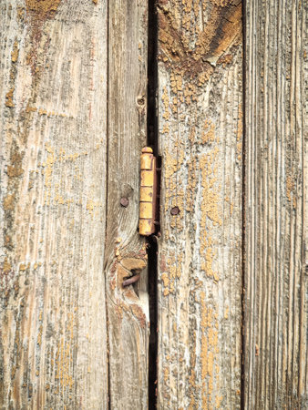 Texture of a wooden plank fence with vertical wood strips, brown wooden fence connection with door hinge backdropの写真素材