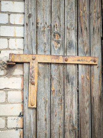 Texture of a wooden plank back door with triangular metal detail between white brick wall and wooden part, brown wooden door connection backdropの写真素材