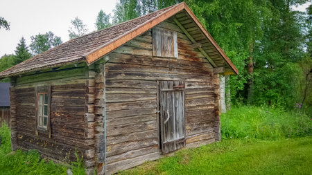 Ancient wooden hut surrounded by greenery in Finland on summer dayの写真素材