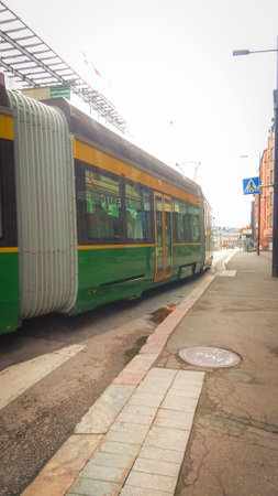Green tram standing on tramway in Helsinki center bottom up view on a dull dayの写真素材
