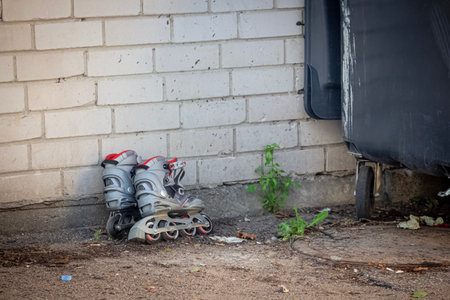 Two roller skates standing near white brick wall outdoorsの写真素材