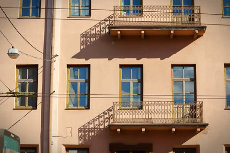 An old balconies casting shadows on brown building in old town with many wires over the road on this streetの写真素材