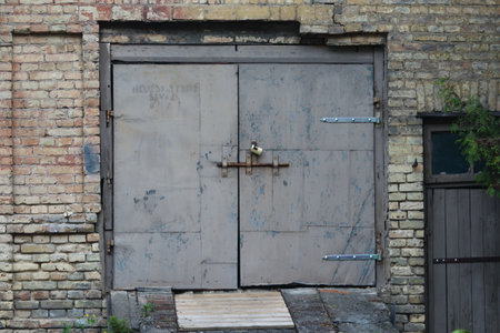 Gray garage door, traditional old town building backyard scenery with brick building wall and old wide door with a padlockの写真素材