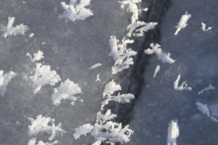 Detailed closeup of natural ice crack patterns creating intricate geometric formations. Perfect for abstract backgrounds, texture design, winter themes, fragility concepts, and natural pattern inspiration.の写真素材