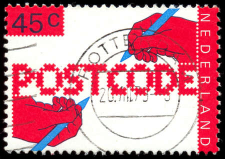 NETHERLANDS - CIRCA 1978: A stamp printed in the Netherlands, dedicated to the Introduction of new postal code, shows the hand of a writing text, circa 1978のeditorial素材