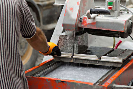 worker and machine cutting a granite blockの写真素材