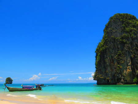 Railay beach, Krabi, Thailand, bright colors on a clear day The background is a long-tailed boat and a deep blue sky.の写真素材