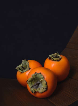 Persimmon on a dark background. Persimmon on a black background.の写真素材