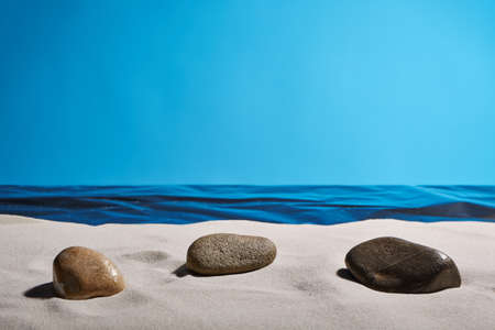 three pebbles on the beach by the sea and a clear blue skyの写真素材