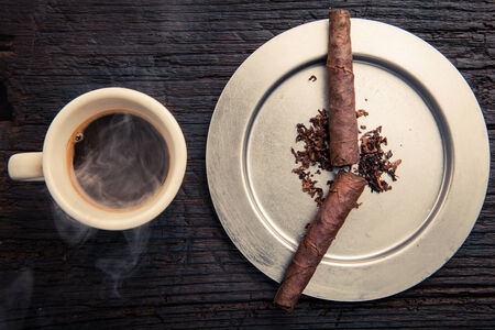 creative composition cigars in the ashtray indicate the seven dl morning like clockwork, beside a cup of espresso and steamingの写真素材