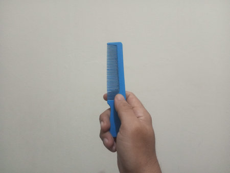 Hand holding a comb on a white background. Close-up.の写真素材