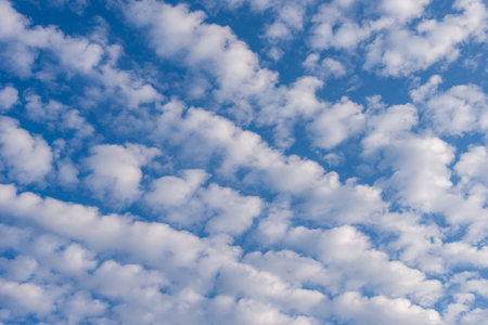 Beautiful weather with a patch of cirrocumulus clouds in a row against the blue sky. Cloud formation