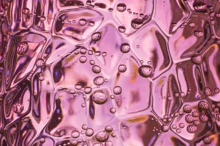 Sparkling water bubbles in a pink hard plastic tumbler. Abstract macro shot with irregular water dropsの写真素材