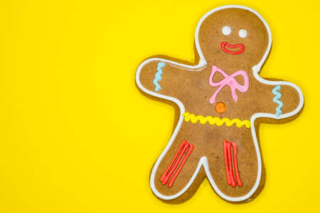 Gingerbread man decorated with colored icing isolated on yellow background with text space.の写真素材