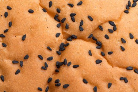 Closeup of nigella seeds on a wheat burger roll. Food background texture.
