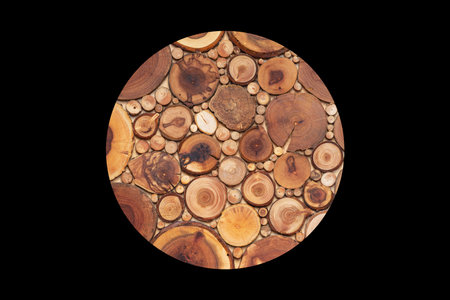 Round pot or hot dish coaster from tiny slices of larch tree isolated on black background. Handmade...