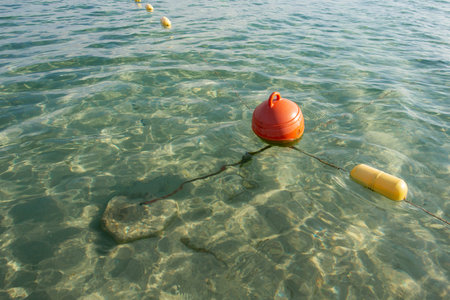 Red floating buoy anchored in the calm lake. Water rescue equipment. Safety water