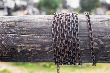 A rusted chain coiled on a rotating beam, a part of an old water wellの写真素材