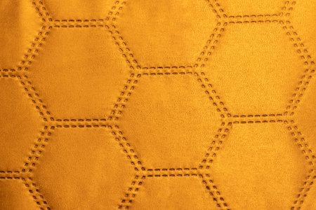 Orange velvet fabric patterned with hexagons resembling soccer ball textureの写真素材