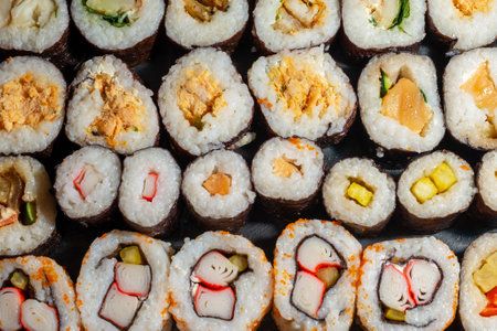 Colorful assortment of sushi rolls arranged in rowsの写真素材