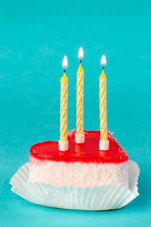 Bright cake in the form of heart with candles on a blue backgroundの写真素材